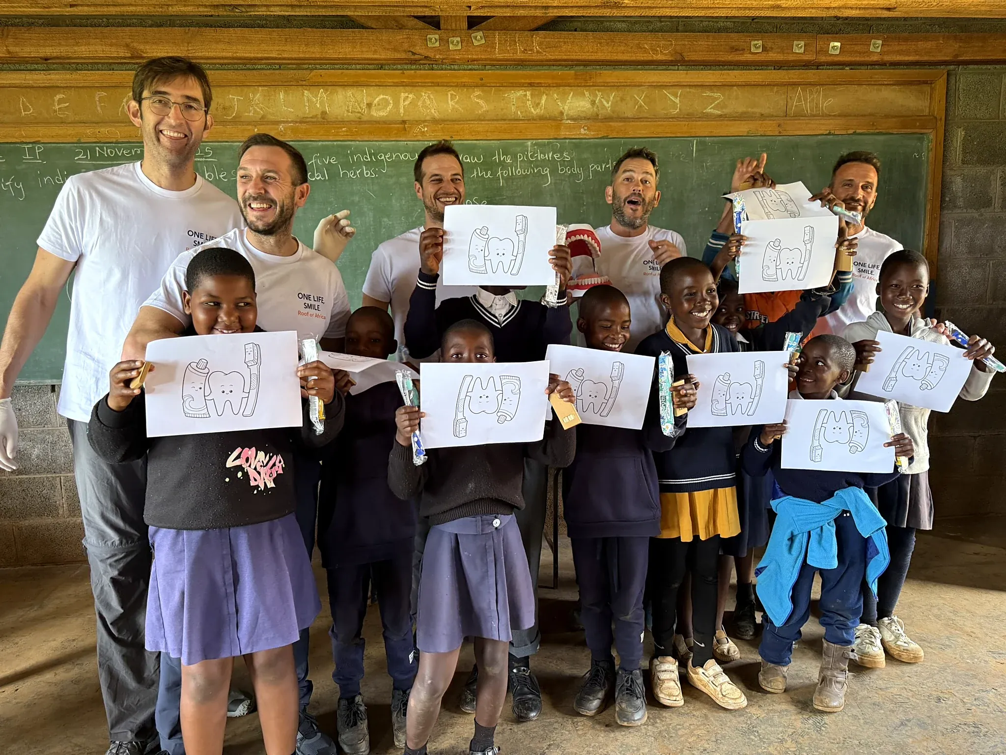 El equipo y los niños de la escuela enseñan sus dibujos de dientes